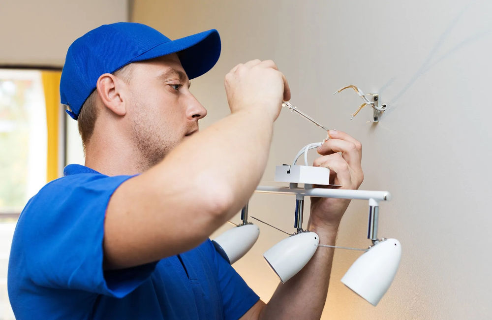 An electrician fixing lights on the wall